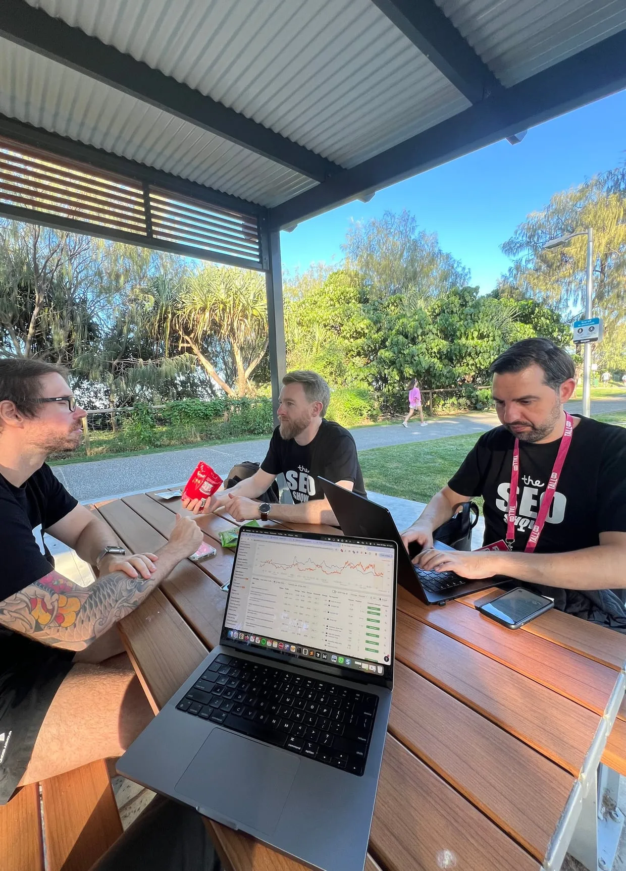 Three of the Local Digital SEO team working on laptops at a park table in Broadbeach