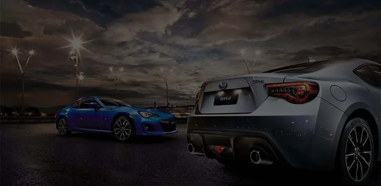 Two Subaru sports cars lit up at night at Bill Buckle Subaru