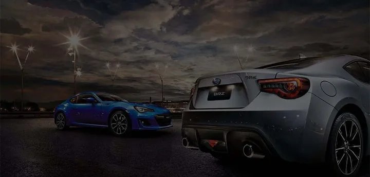 Two Subaru sports cars lit up at night at Bill Buckle Subaru