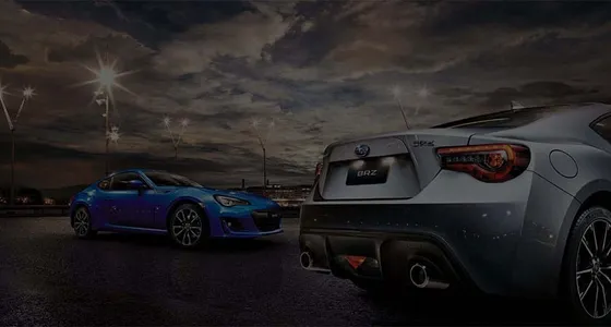 Two Subaru sports cars lit up at night at Bill Buckle Subaru