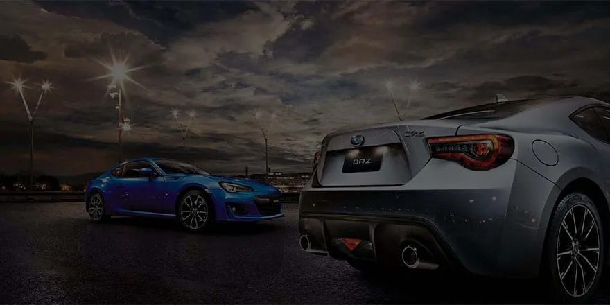 Two Subaru sports cars lit up at night at Bill Buckle Subaru