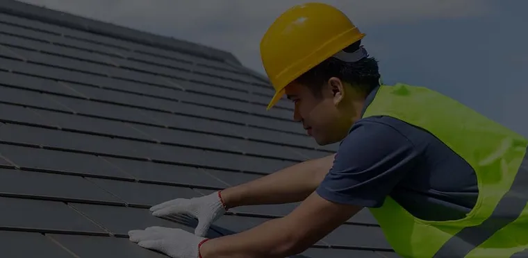 A First Class Slate roofer in hi-vis working on a slate roof