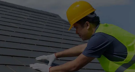 A First Class Slate roofer in hi-vis working on a slate roof