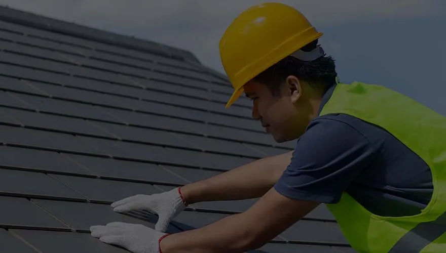 A First Class Slate roofer in hi-vis working on a slate roof